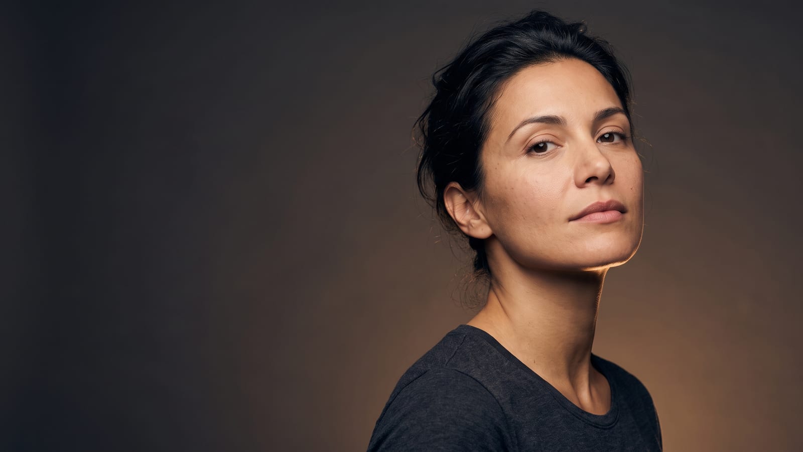 Woman turning back toward the camera with the light along a slim, softly defined jawline — how long masseter Botox lasts, at a Highland Park med spa