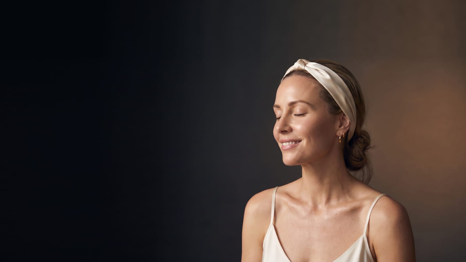 Woman in a silk facial headband with fresh, hydrated glowing skin after a HydraFacial at DK Aesthetics Highland Park IL